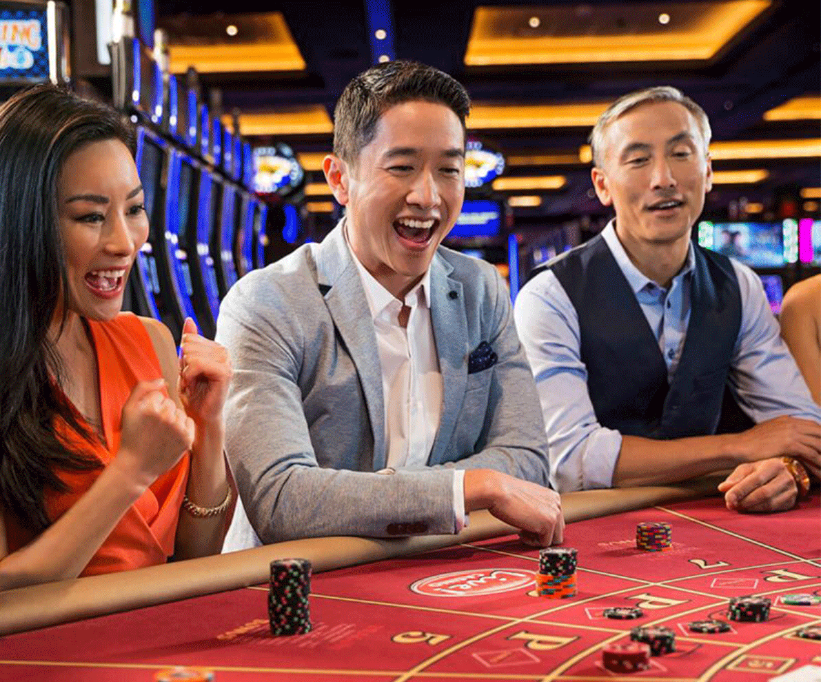 Красивая азиатка в красном платье и двое азиатских мужчин играют в баккара в зале престижного казино в Лаосе