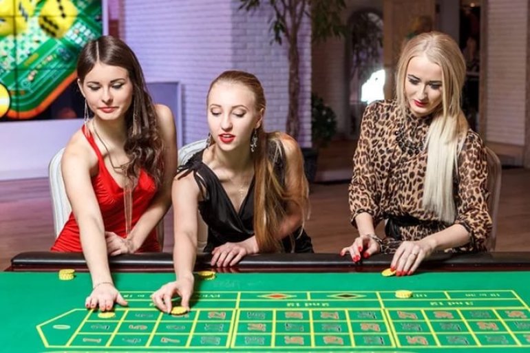 Трое симпатичных женщин за игрой в рулетку в казино