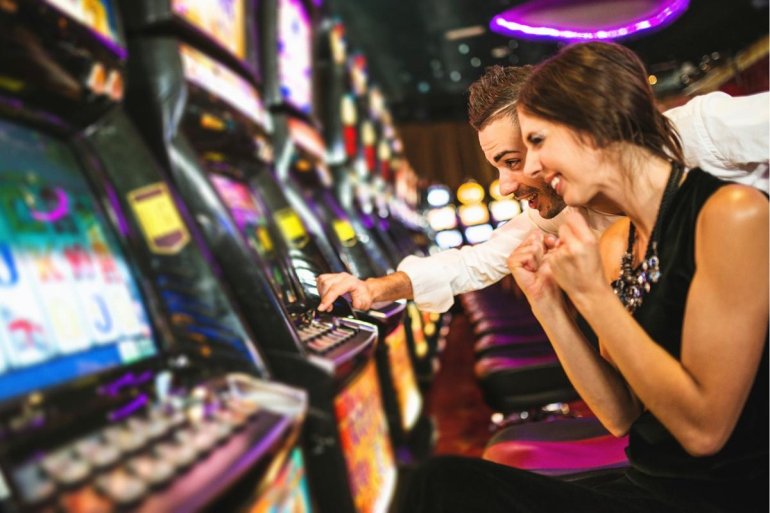 Влюбленная парочка играет на автоматах в престижном казино