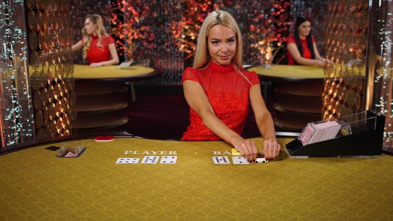 Сексуальная блондинка в красном в ожидании игроков за столом для баккара