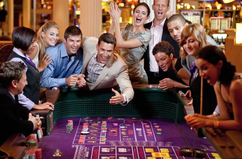 Компания молодых красивых людей играет в крэпс в казино