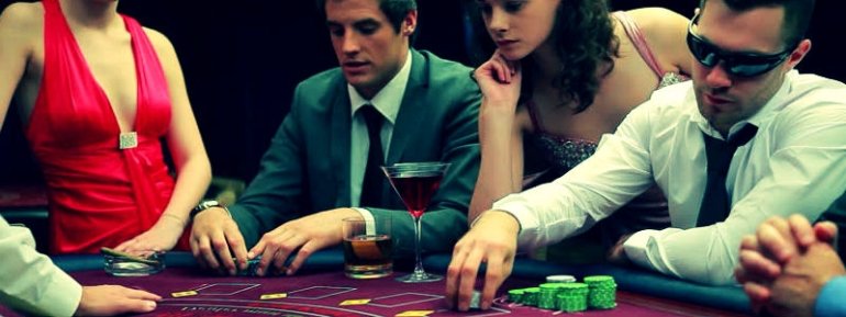 Игроки за столом для блэкджека наслаждаются компанией красоток и пьют алкоголь