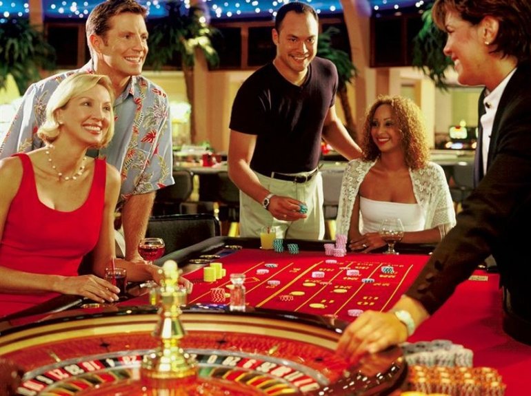 Компания красивых молодых людей за игрой в рулетку в казино