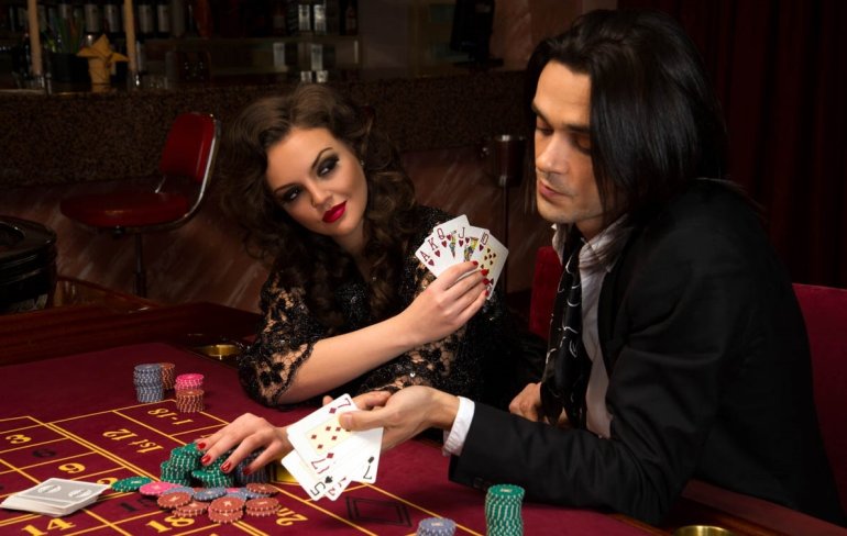 Сексуальная шатенка играет в казино за одним столом с молодым обеспеченным мужчиной с темными волосами и пытается флиртовать за игрой
