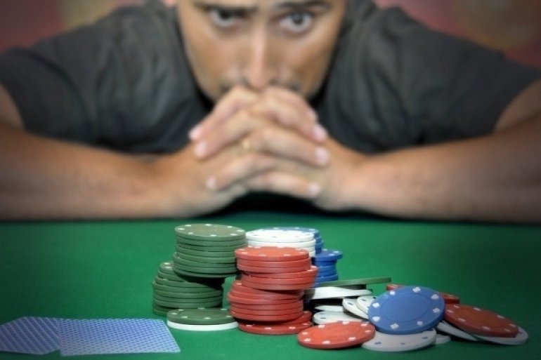 Озадаченный игрок смотрит на фишки и карты, разложенные на столе