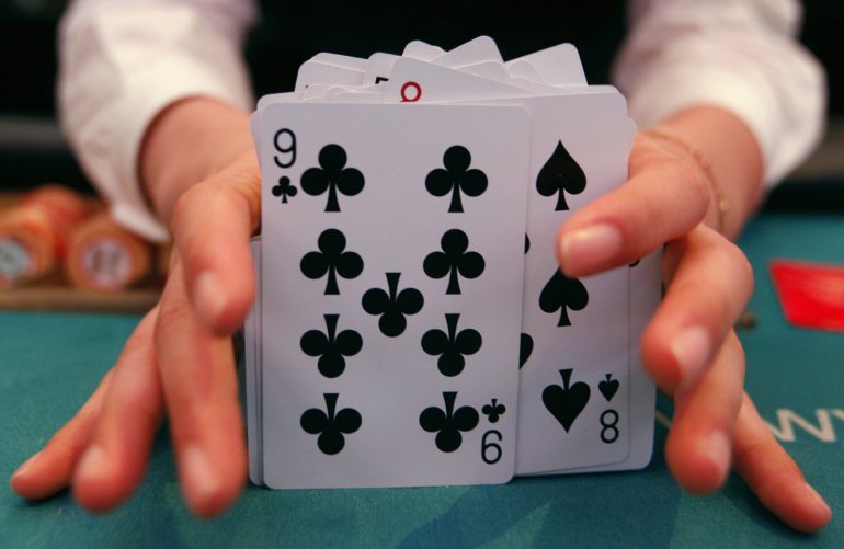 Руки дилера, выставившие колоду карт на обозрение игрокам