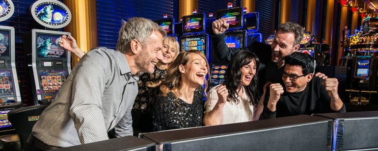 Девушки и парни отрываются за игрой на слотах в престижном казино