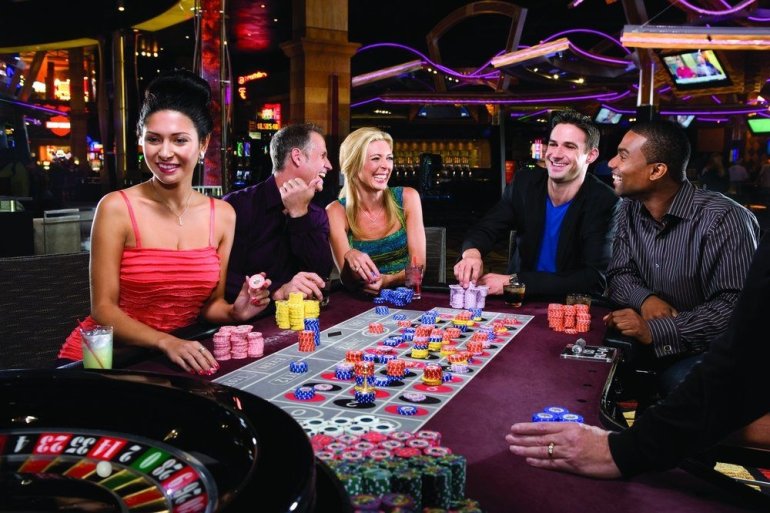 Люди разных национальностей в нарядной одежде играют в рулетку в престижном казино Вашингтона
