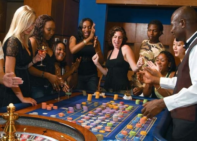 Темнокожие люди и европейцы веселятся за игрой в рулетку в престижном казино
