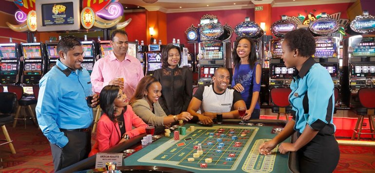 Компания темнокожих людей хорошо проводит время за игрой в рулетку в престижном казино на курорте