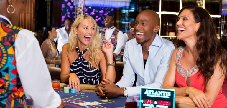 Темнокожий парень развлекается в казино за игрой в блэкджек с брюнеткой и блондинкой