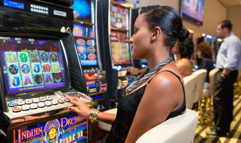Темнокожая девушка за игрой на автомате в зале престижного казино