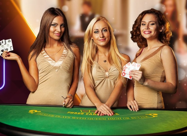 Три красотки в обтягивающих бежевых платьях позируют у игорного стола для трехкарточного покера с картами в руках