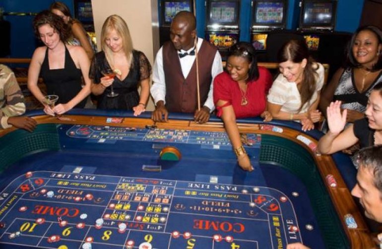 Темнокожий крупье ведет игру в крэпс для клиентов казино