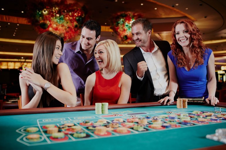 Блондинка, шатенка и рыжая веселятся за игрой в рулетку в компании двух богатых мужчин