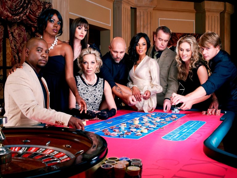 Нарядные мужчины и женщины разных национальностей играют в рулетку в зале дорогого казино