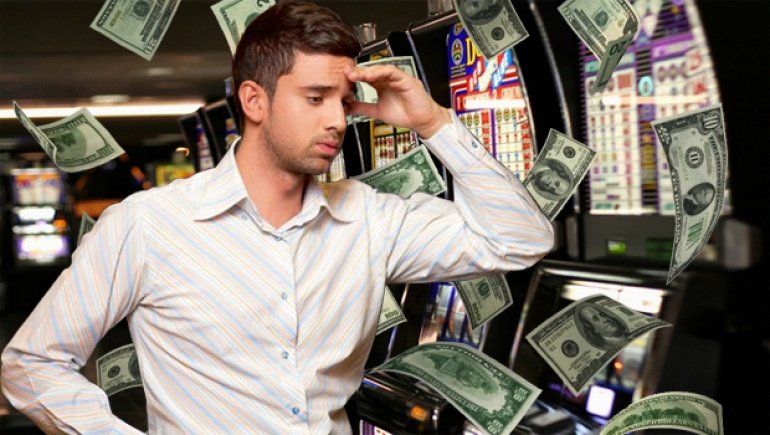 Мужчина сидит у игрового автомата, а вокруг летают долларовые купюры