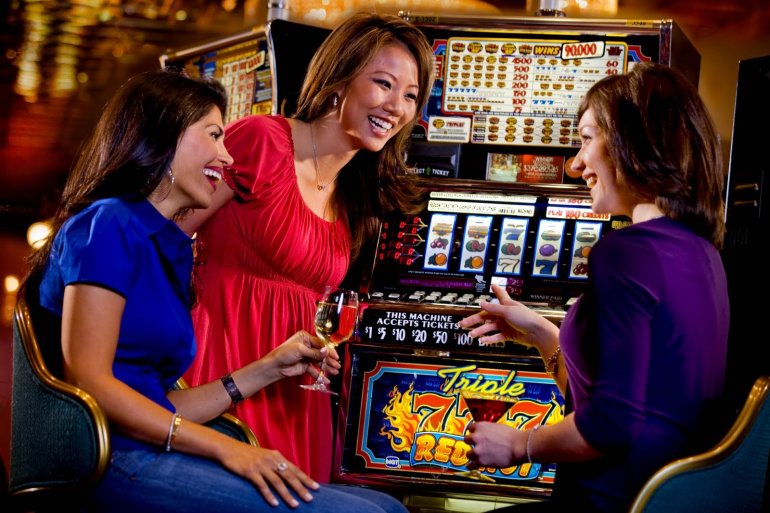 Трое подруг в приподнятом настроении собираются сыграть на автомате в зале казино