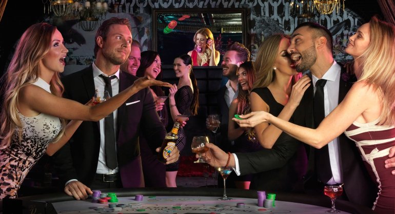 Мужчины и женщины пьют в казино за игрой в рулетку