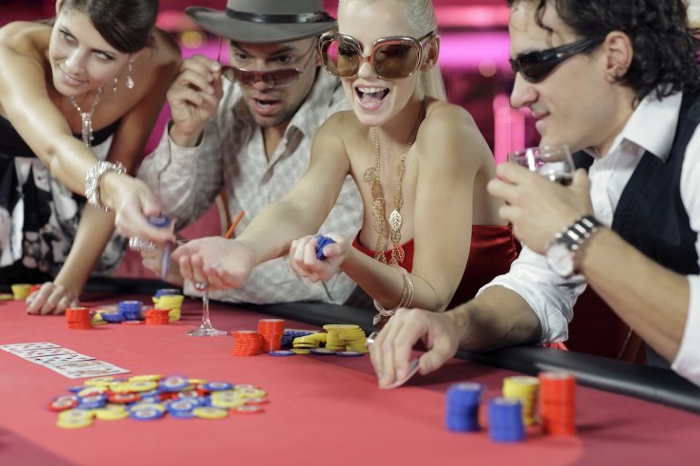 Веселая компания чудит за игорным столом в казино, развлекаясь и развлекая все вокруг