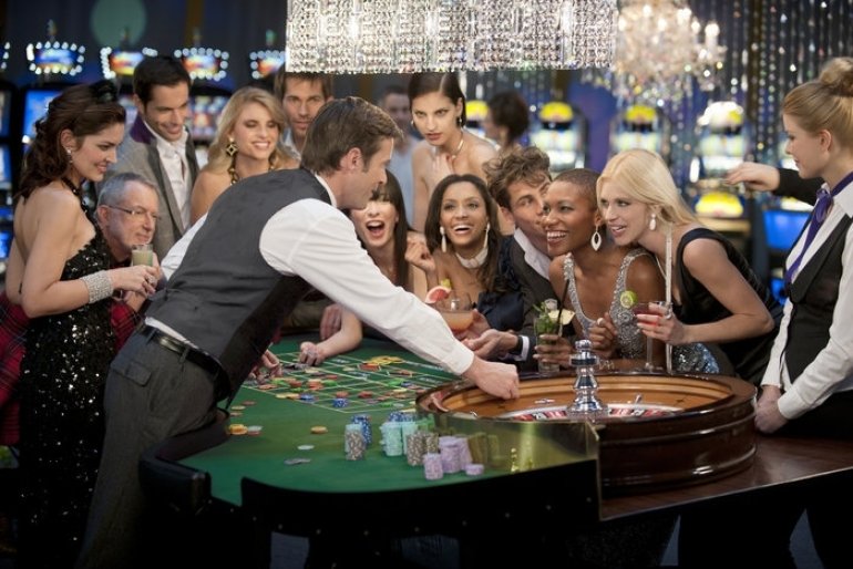 Элитные дамы и мужчины в вечерних нарядах за игрой в казино