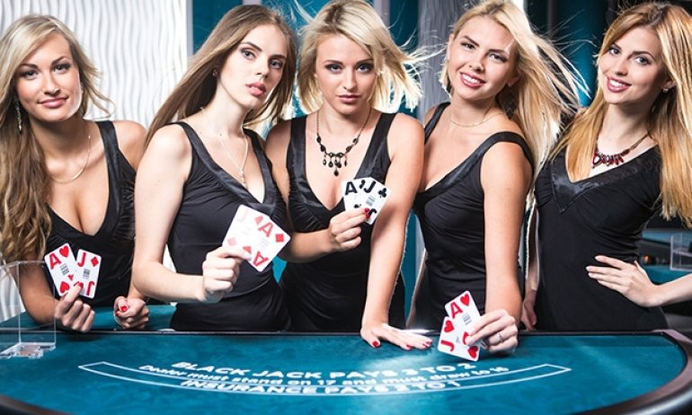 Пятеро блондинок крупье в сексуальных черных платьях позируют у игрного стола с картами в руках