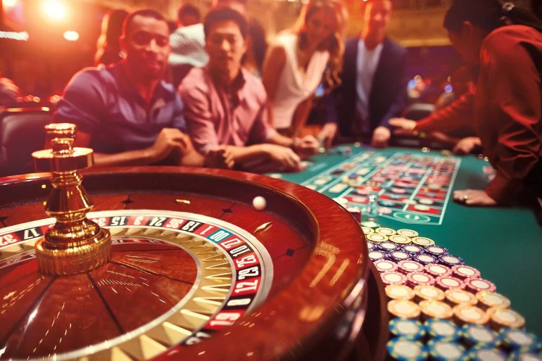 Колесо рулетки и азартные игроки за столом на заднем фоне