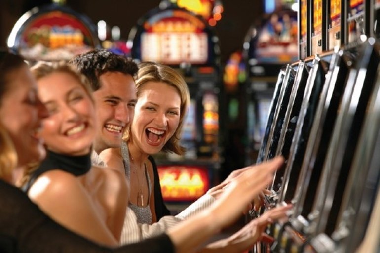 Смеющиеся люди за игрой на автоматах в казино
