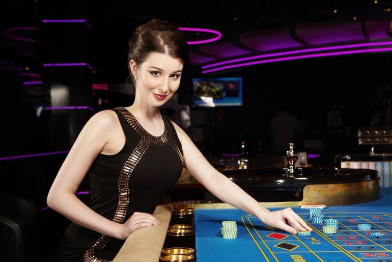 Брюнетка в вечернем платья за игрой в рулетку в красивом казино