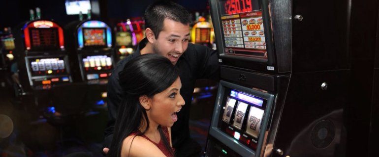 Парень и девушка в азарте за игрой на автомате в дорогом престижном казино