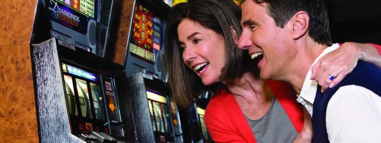 Женщина и мужчина обнимаются, радуясь своему выигрышу на игровом автомате